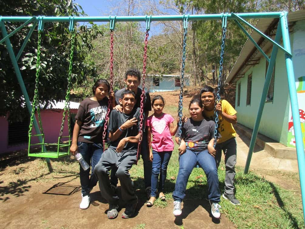 Raúl poses on the swings with his COAR family - 2018